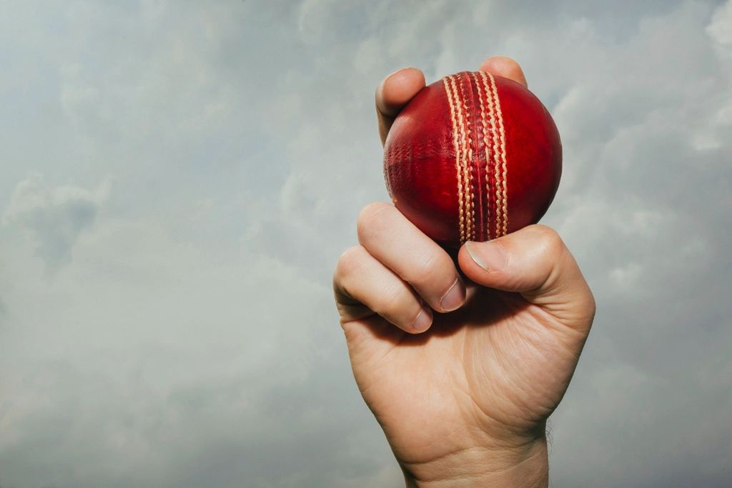 Hand holding a red cricket ball